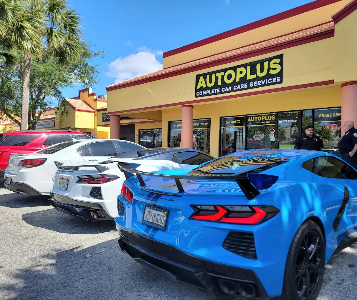 AutoPlus Complete Car Care Services storefront in Lauderhill, FL with a blue Corvette and customer cars out front