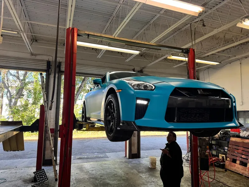 Blue Nissan GT-R on a two-post lift at AutoPlus