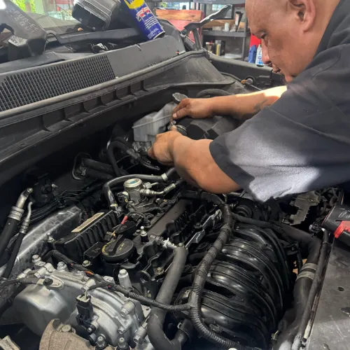 AutoPlus technician working under the hood of a customer's car